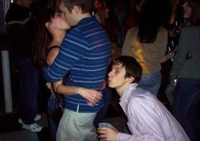 Парень и девушка целуются, третий пьет из ее бокала